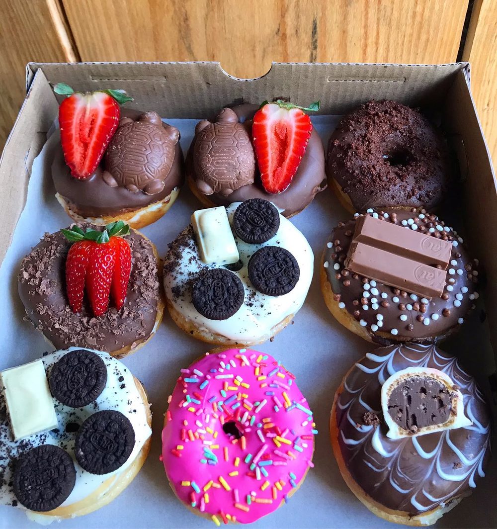 Caixa aberta com donuts de morango, Oreo, Kit-Kat, chocolate e granulado colorido